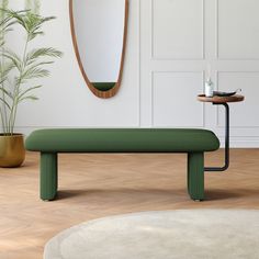 a green bench sitting in front of a mirror next to a table and potted plant