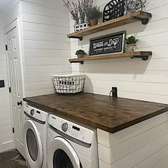 a washer and dryer in a small room with shelves on the wall above them