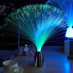 two lit up vases sitting on top of a wooden table next to a cup and saucer