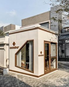 a small house with an open window on the outside and brick walkway in front of it