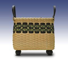 a woven basket sitting on top of a wooden cart with handles and two black handles