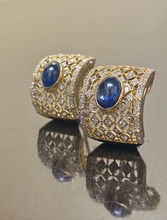 DeKara Designs Collection Metal- 18K White Gold, .750. 15.50 Grams. Stones- 2 Genuine Cabochon Oval Ceylon Blue Sapphires 5.02 Carats, 168 Round Diamonds F-G Color SI2 Clarity 2 Carats. One of a kind entirely handmade, Art Deco 18K Yellow Gold Sri Lanka Ceylon Cabochon Cut Blue Sapphire and Pave Set Diamond Art Deco Inspired One of a Kind Earrings. Each earring has an amazing oval cabochon blue sapphire that is professionally and uniquely bezel/burnish set. There are 79 round pave set diamonds o Luxury Diamond Cabochon Earrings, Luxury Diamond Earrings With Cabochon, Oval Sapphire Earrings With 17 Jewels, Luxury Formal Clip-on Earrings With Cabochon, Luxury Cabochon Clip-on Earrings For Formal Occasions, Luxury Oval Yellow Gold Earrings, Luxury Yellow Gold Oval Earrings, Luxury Sapphire Yellow Gold Earrings, Luxury Oval Clip-on Earrings For Anniversary