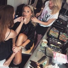 three women are sitting at a counter getting their make - up done in front of them