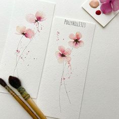 two cards with watercolor flowers on them next to a paintbrush and flower stamp