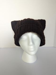 a white mannequin head wearing a brown knitted cat ear hat with ears