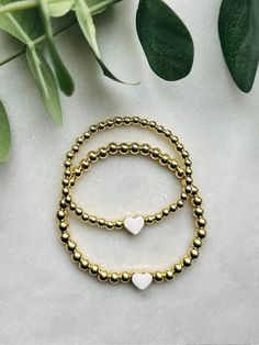 Sweet and adorablematching mother daughter bracelet set. These 18k gold filled bracelets are centered with a white enamel and gold heart. Perfect gift for a new mom and daughter or for mom to gift her little on. Bracelets are beaded on high quality stretch cord and secured.  - 4mm 18k gold filled beads    5mm 18k gold filled beads   8mm enamel heart bead  - If you need more then 1 mini, please send me a message for a custom listing  - Each purchase is sent in a velvet drawstring bag making the p Dainty White Heart Bracelet For Anniversary, White Heart Charm Bracelet For Anniversary, Nickel-free Gold Name Bracelet For Everyday, White Bracelets With Heart Charm For Anniversary, Dainty Gold Stackable Name Bracelet, White Dainty Jewelry For Valentine's Day, White Hypoallergenic Name Bracelet For Anniversary, Dainty White Jewelry For Valentine's Day, Hypoallergenic White Name Bracelet For Anniversary