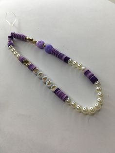 two purple and white beaded necklaces sitting on top of a table