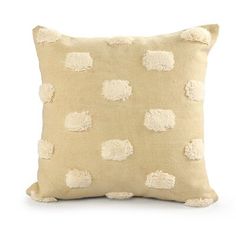 a beige pillow with pom - poms on the front and back, against a white background