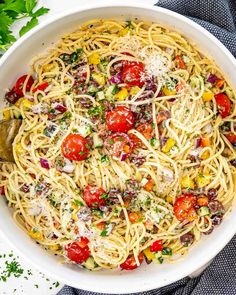 a white bowl filled with pasta, tomatoes and parmesan cheese topped with parsley