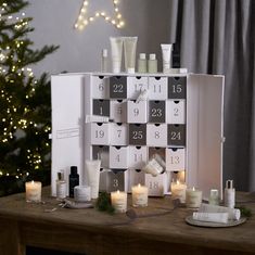 a wooden table topped with lots of different types of skin care products next to a christmas tree