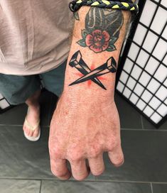 a person with a tattoo on their arm holding two crossed swords in front of them