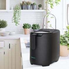 an air purifier sitting on top of a kitchen counter next to potted plants