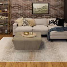 a living room with a couch, coffee table and rug on the floor in front of a brick wall