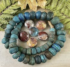 a group of bracelets sitting on top of a table next to green plants and leaves