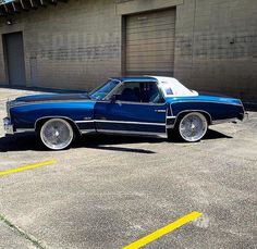 a blue and white car parked in a parking lot next to a building with garage doors