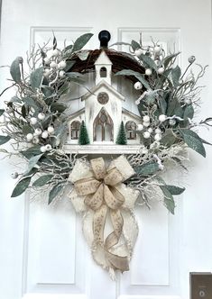 a wreath is hanging on the front door with a church and evergreens around it