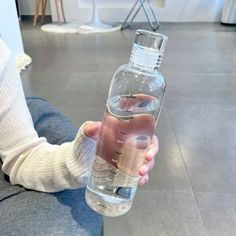 a person is holding a water bottle in their left hand while sitting on the floor