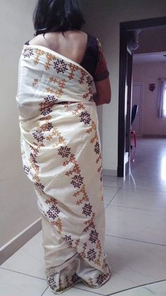 a woman in a white sari is looking into the mirror