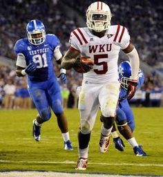 a football player running with the ball in his hand and other players on the field behind him