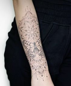 a woman's arm with a tattoo on it that has an intricate lace design