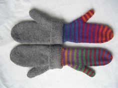 two knitted mittens sitting on top of a white cloth covered tablecloth, one with multi - colored stripes