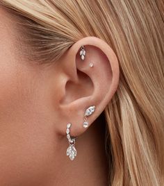 a close up of a woman's ear with three small diamond earrings on it