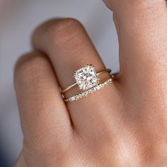 a woman's hand with a diamond ring on top of her finger and an engagement band