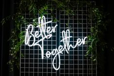 there is a sign that says better together on the side of a fence with greenery around it