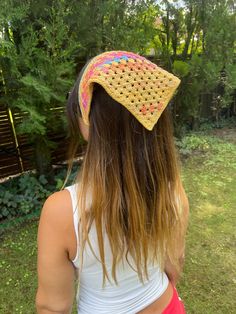 the back of a woman's head wearing a crochet hat in front of trees