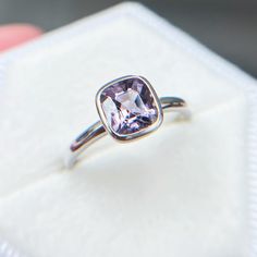 an engagement ring with a pink diamond in it sitting on a white cloth napkin,