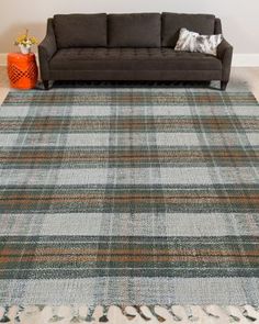 a living room with a couch and rugs on the floor in front of a wall