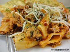 a white plate topped with pasta covered in sauce and cheese next to a silver fork