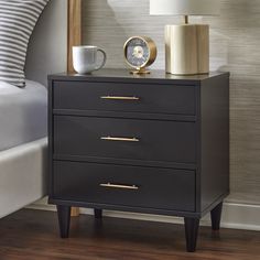 a night stand with two drawers and a clock on the top one is next to a bed