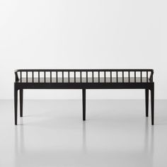 a black bench sitting on top of a white floor in front of a white wall