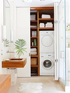 a washer and dryer in a small room with shelves full of towels on the wall