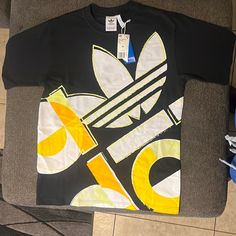 Adidas Casual Athletic Tee New With Tags Multicolor Logo Print Top For Streetwear, Urban Yellow T-shirt With Letter Print, Yellow Sporty T-shirt With Letter Print, Casual Yellow T-shirt With Letter Print, Yellow Sporty Crew Neck Tops, Adidas Multicolor Short Sleeve Tops, Adidas Urban T-shirt For Streetwear, Sporty Multicolor Adidas Tops, Adidas Sporty Multicolor Tops