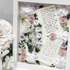 paper flowers are arranged in a shadow box with a note inside and writing on it