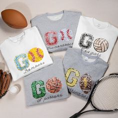 four t - shirts with the names of different countries on them and a tennis racket