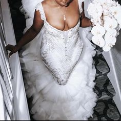 a woman in a wedding dress is walking down the stairs with flowers on her hand