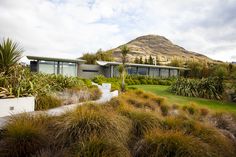 the house is surrounded by lush green plants and mountains in the backround area