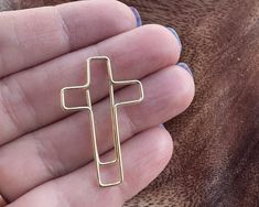 a person holding a cross shaped pin in their left hand and wearing a ring on the other