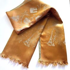 This is a vintage silk satin scarf with a distinct bronze light brown shimmery color. The color may be slightly different on your device. The scarf is short, but wide and can be folded into two. It measures: 12.5x46 inches. It features the major attractions of Paris - Eiffel Tower, Notere-Dame, Opera, Arc De Triomphe, Sacre-Coeur, etc. The pattern on the scarf seems to be embossed into the fabric giving it a beautiful effect of photography. The scarf is in very good condition and can be used by Luxury Brown Scarves For Formal Occasions, Luxury Brown Elegant Scarves, Luxury Brown Pashmina Scarf, Luxury Brown Pashmina Scarves, Luxury Brown Classic Silk Scarf, Luxury Classic Brown Silk Scarf, Luxury Brown Silk Scarf, Paris Design, Brown Silk