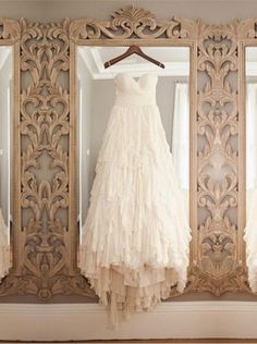 a wedding dress hanging in front of a mirror