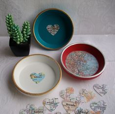 three bowls and two plates on a table with small succulents in them