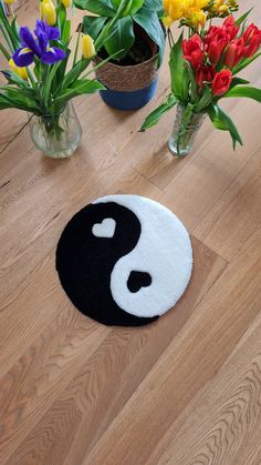 a black and white rug sitting on top of a wooden floor next to vases filled with flowers