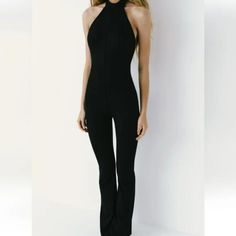 Full Length Jumpsuit Made Of Technical Fabric. Halter Neckline And Open Back. Button Closure At Neck And Hidden In Seam Zipper At Back Casual Fitted Strapless Jumpsuit For Evening, Casual Evening Strapless Jumpsuit, Fitted Black Overall Jumpsuits And Rompers, Fitted Black Overall Jumpsuit, Fitted One-piece Jumpsuits For Workwear, Chic Fitted Overalls And Jumpsuits, Black Fitted Overall Jumpsuit, Fitted Overall Pantsuit For Date Night, Fitted Black Summer Pantsuit