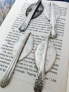 three spoons and two forks sitting on top of an open book