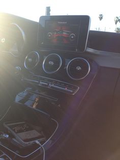 the interior of a car with an electronic device in it's center console and sun shining through the windshield