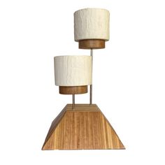 two white lamps sitting on top of a wooden stand with one lamp turned upside down