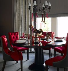 a dining room table with red chairs around it